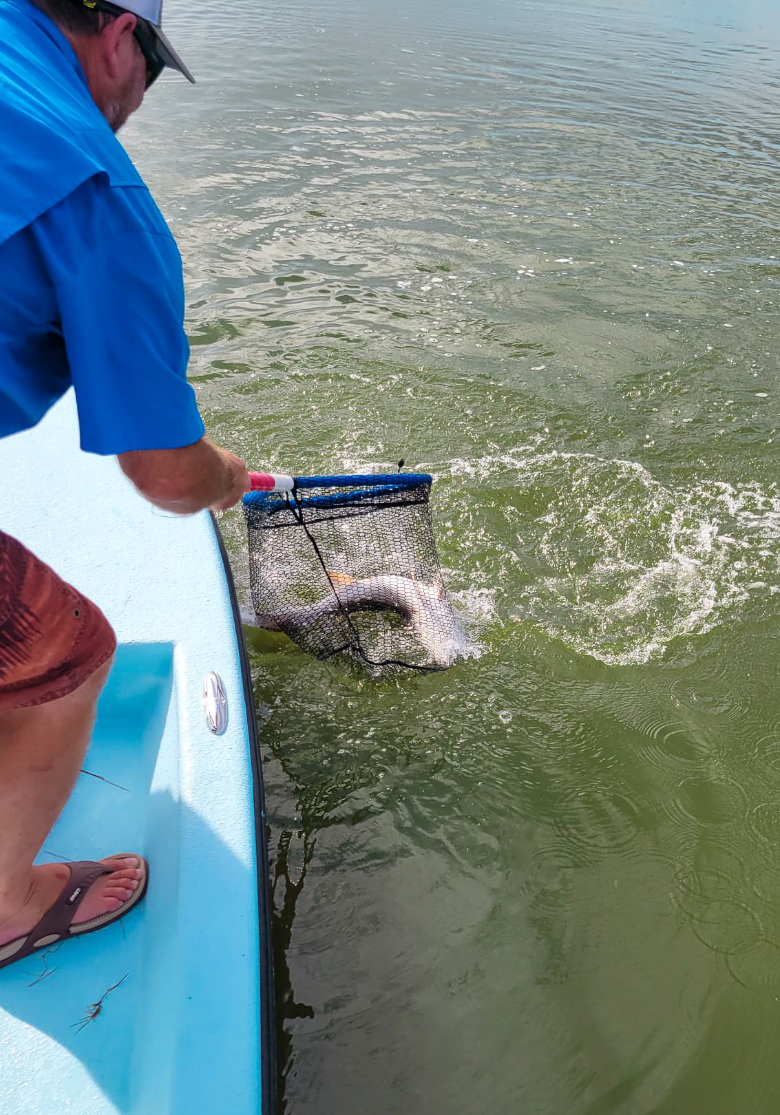 Guide netting a redfish beside a Port O'Connor bay boat